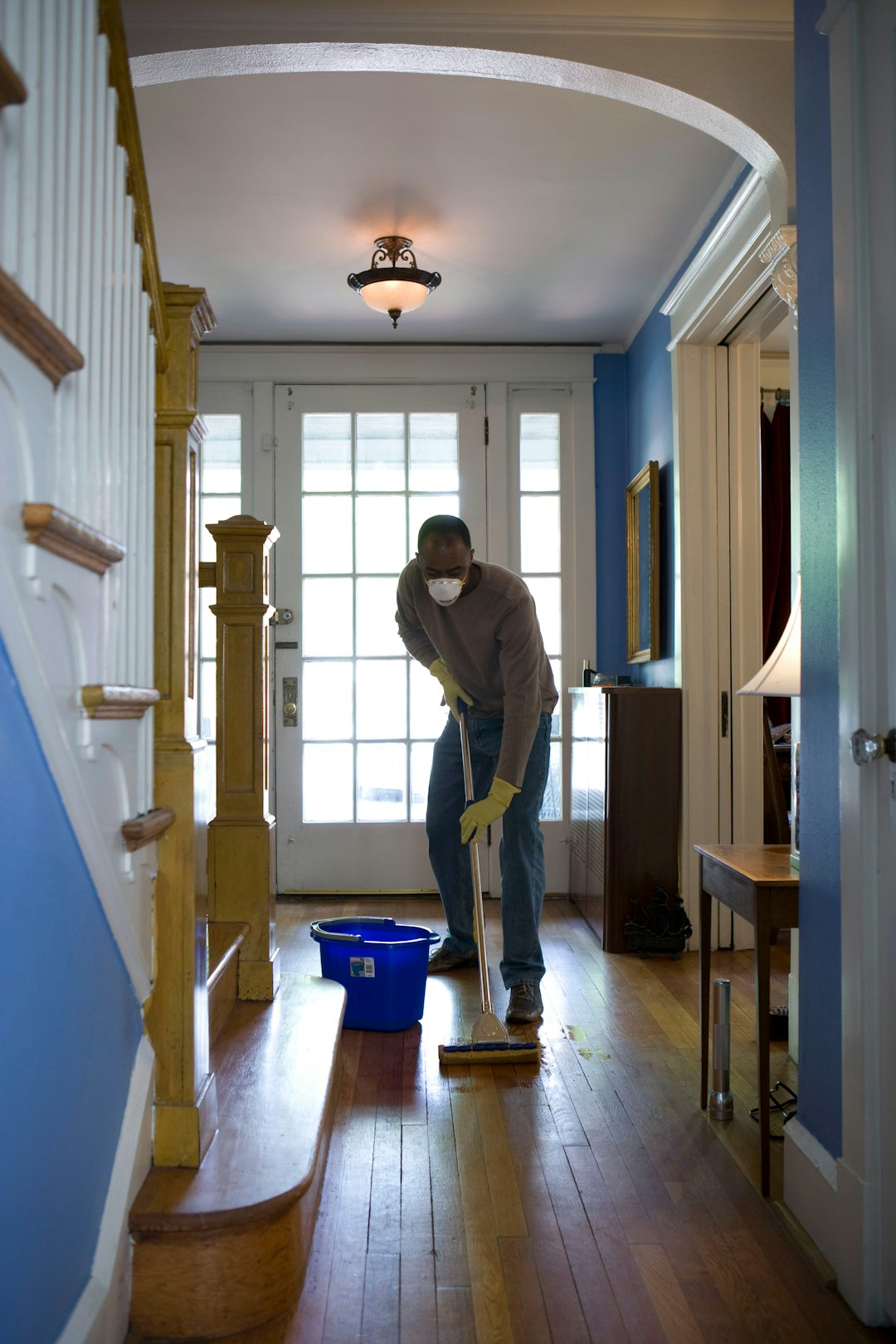 creative This African-American man was in the process of damp-mopping his home’s entrance way. In this way airborne particulates including dust and pollen, could be removed from the inside of his home, thereby, reducing the detrimental effects these substances have upon the respiratory system of his family members. These irritants can sometimes result in sinus infections, and asthma.