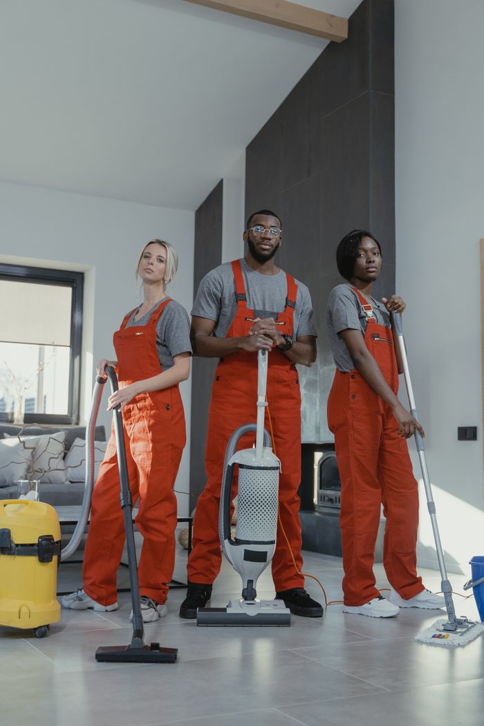 Services-01 Three cleaners in uniform with equipment in a modern home interior, showcasing teamwork and professionalism.